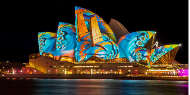 FAMOUSE AUSSIE OPERA HOUSE IN SYDNET=Y BASKING IN AN EXOTIC ARRAU OF COLOR SPARKING AT NIGHT