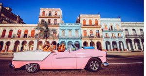 CUBAN VACATION TRAVELERS IN AN OLD PINK CAR