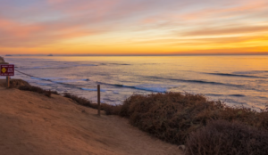 BEAUTIFUL SAN DIEGO COASTLINE ATTRACTS SAN DIEGO TOURIISTS AND WORLD TRAVELERS AGAINST A GORGEOUS GOLDEN SUNSET