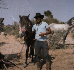 DUDE RANCHER STANDING NEXT TO HIS HORSE